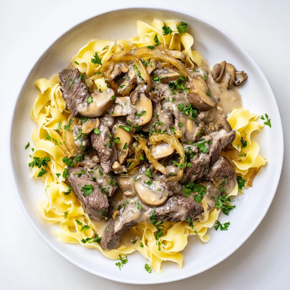Beautiful image of golden egg noodles topped with flavorful Beef Stroganoff, ready to serve.
