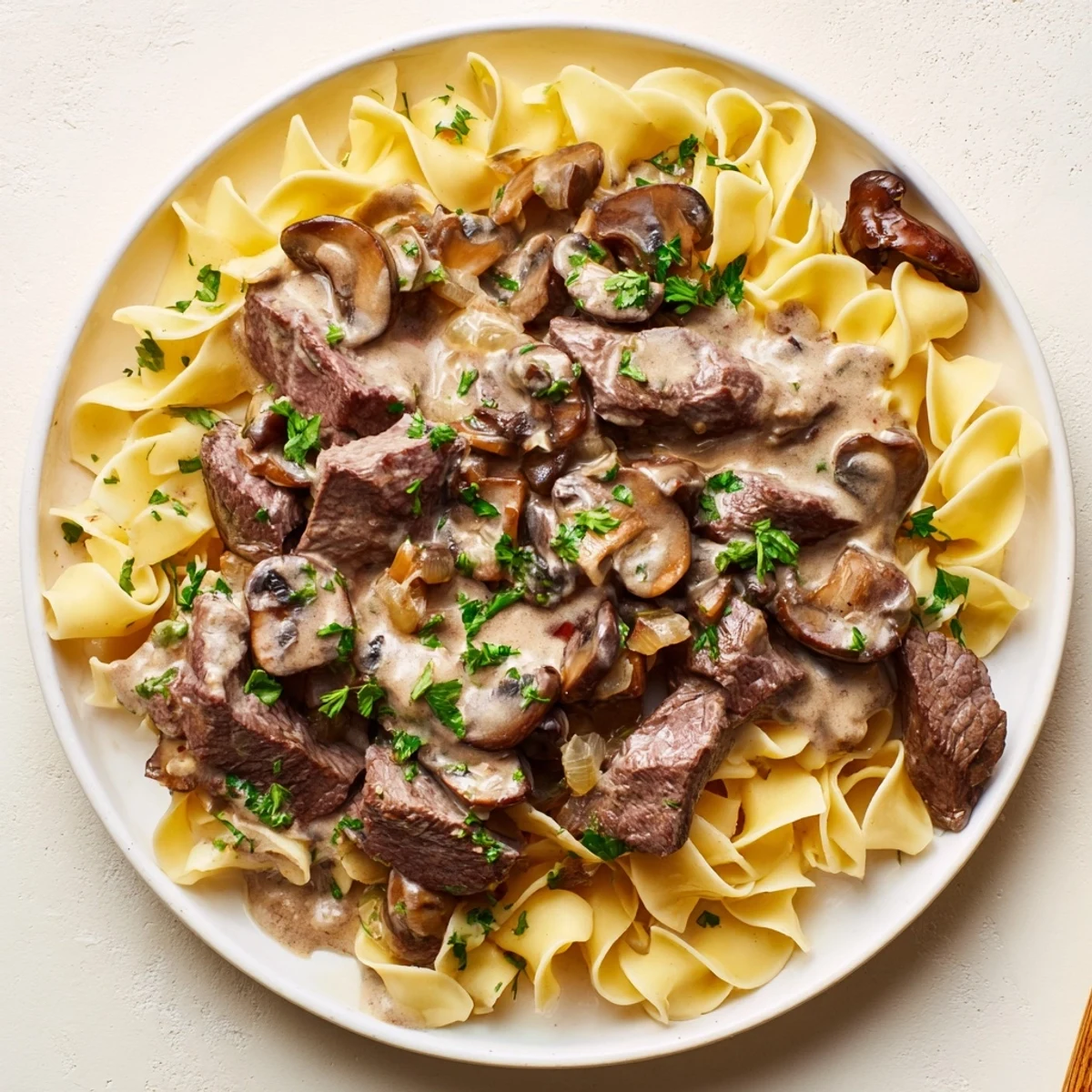 Enjoy a comforting bowl of Beef Stroganoff over egg noodles, steaming hot and ready to eat.