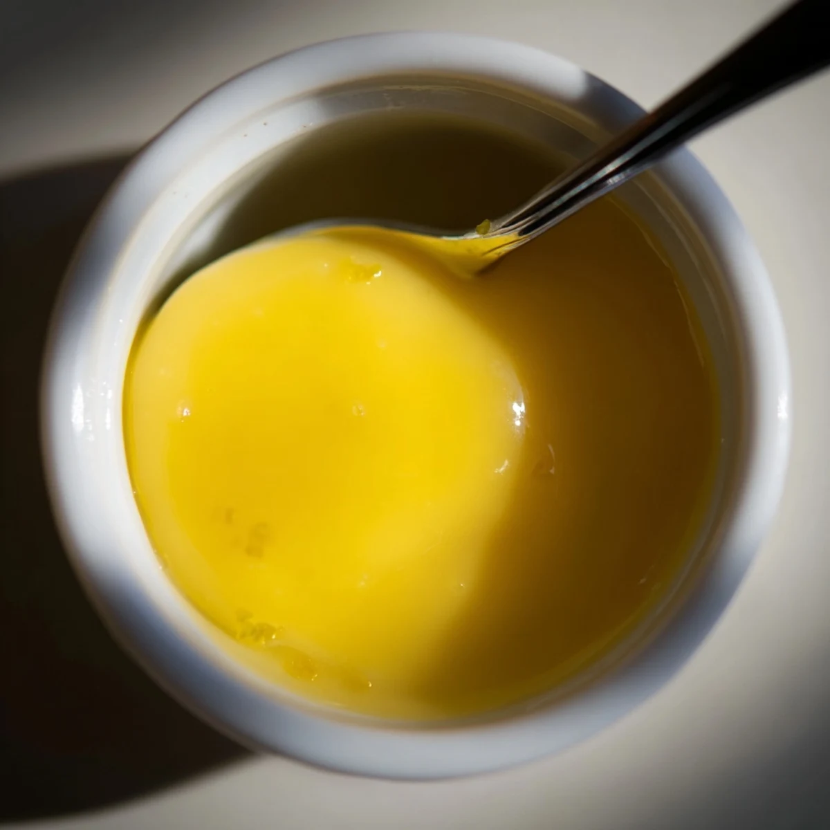 Homemade lemon curd with butter in a jar, garnished with fresh lemon zest.