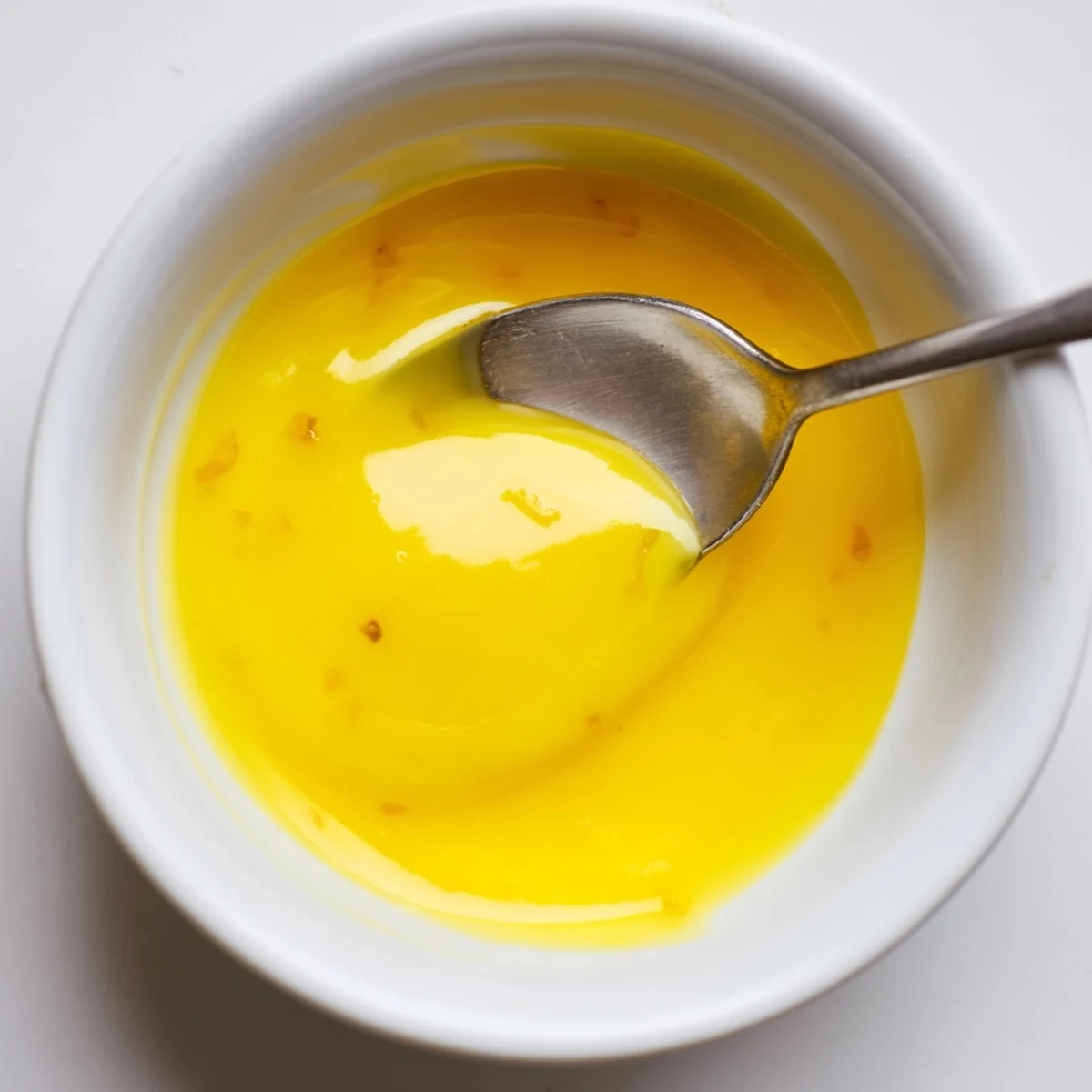 Lemon curd with butter spread on a toasted slice of bread on a plate.