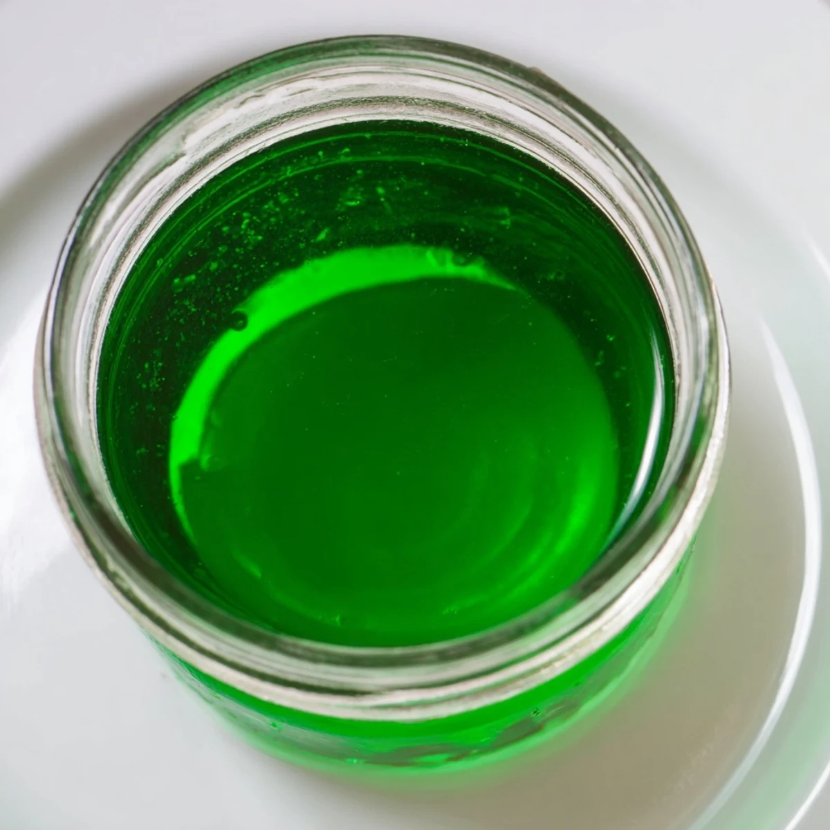 Bright green Peppermint Schnapps syrup glistens in a jar, ready for mocktails.