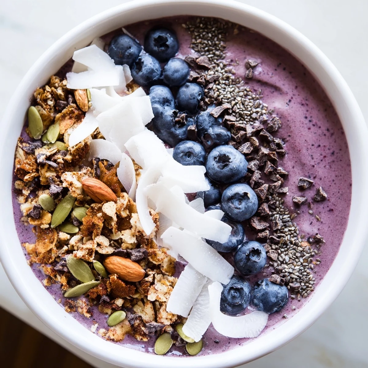 Thick Winter Berry Smoothie Bowl topped with crunchy granola, fresh berries, and sliced almonds for a vibrant breakfast.