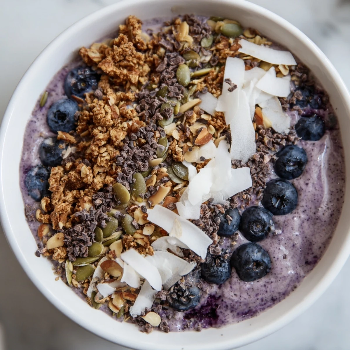 A nourishing Winter Berry Smoothie Bowl served with granola and cacao nibs, perfect for a refreshing morning meal.