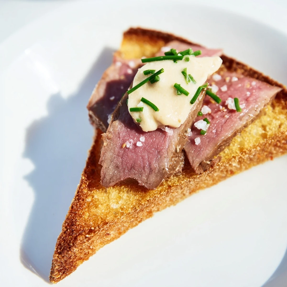 Buttery, crispy toast triangles arranged on a platter with savory beef and a dollop of zesty horseradish cream, ready to serve.