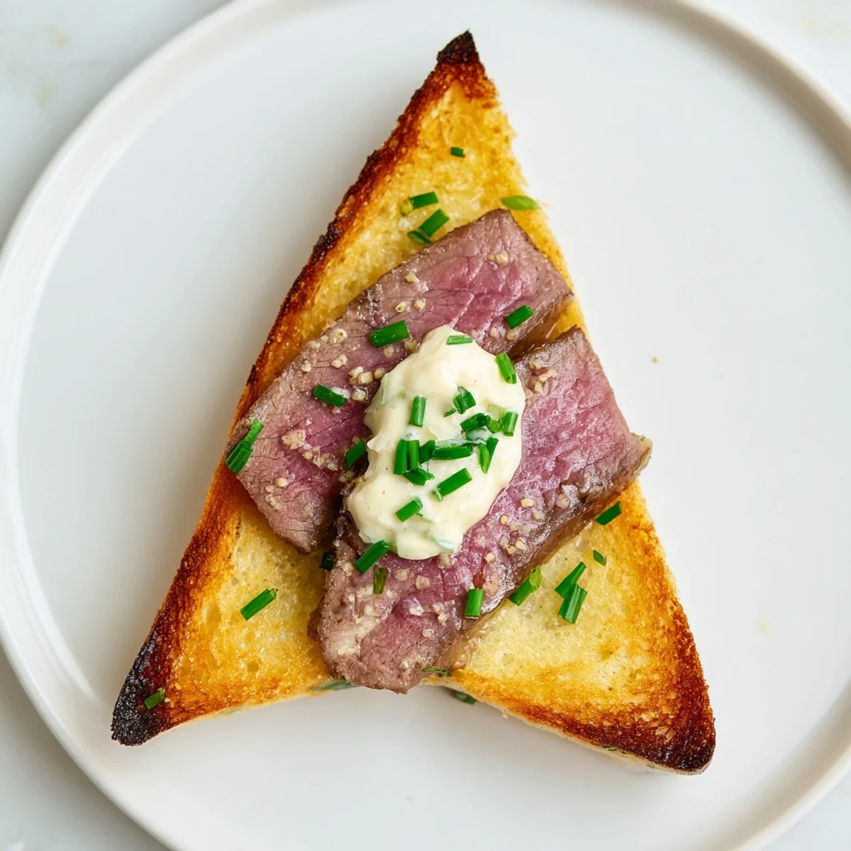 Freshly prepared Beef Toast Points featuring juicy beef, smooth tangy sauce, and flaky sea salt, ideal for an elegant appetizer spread.