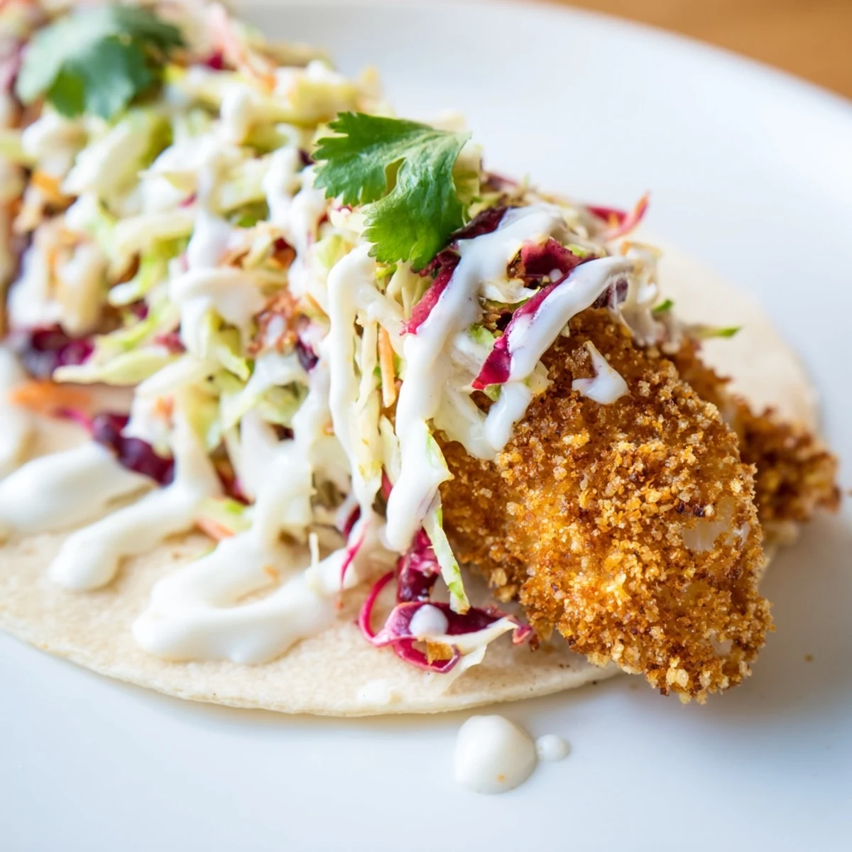 Warm corn tortillas hold Crispy Fish Tacos with Cabbage Slaw, paired with a cold beer and vibrant limes.