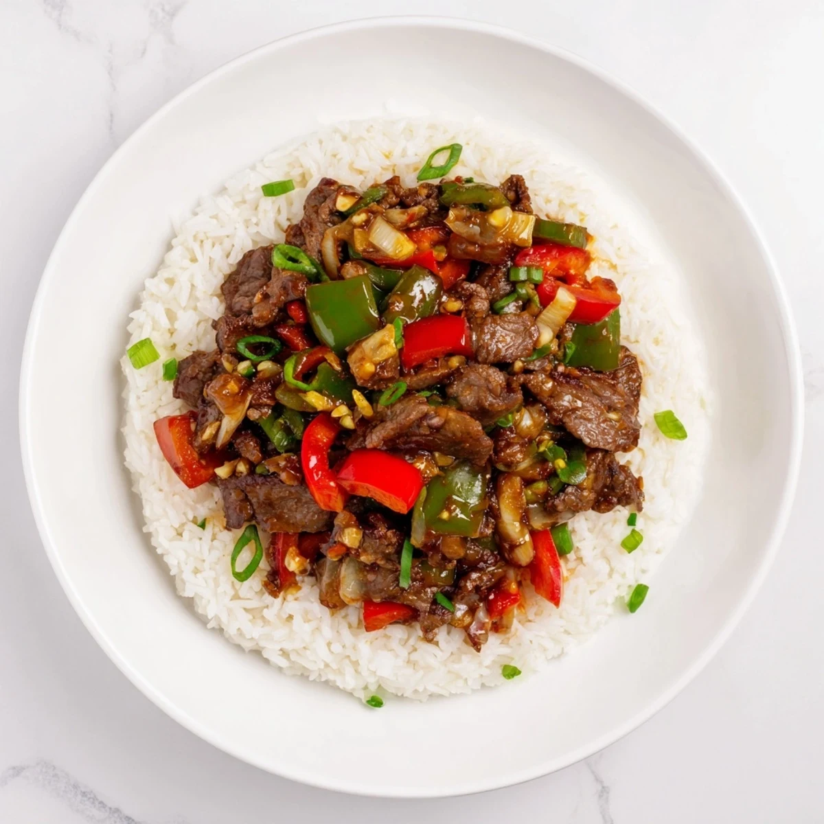 A close-up of juicy beef and crisp vegetables in a glossy sauce over steamed rice.