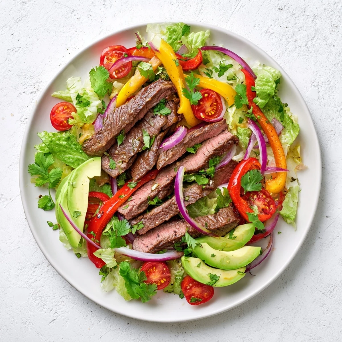 Colorful Beef Fajita Salad with grilled steak, crisp romaine, bell peppers, and creamy avocado on a platter.  