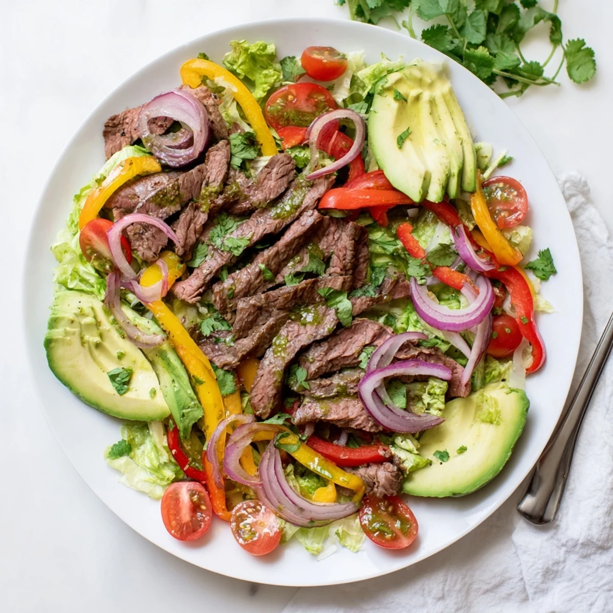 Plated Beef Fajita Salad with bright lime dressing, red onion, and a sprinkle of smoky spices.