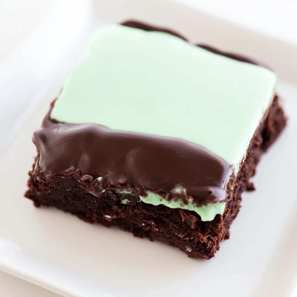 Shamrock Mint Brownies with Chocolate Ganache garnished with crushed mint candies on a wooden board.