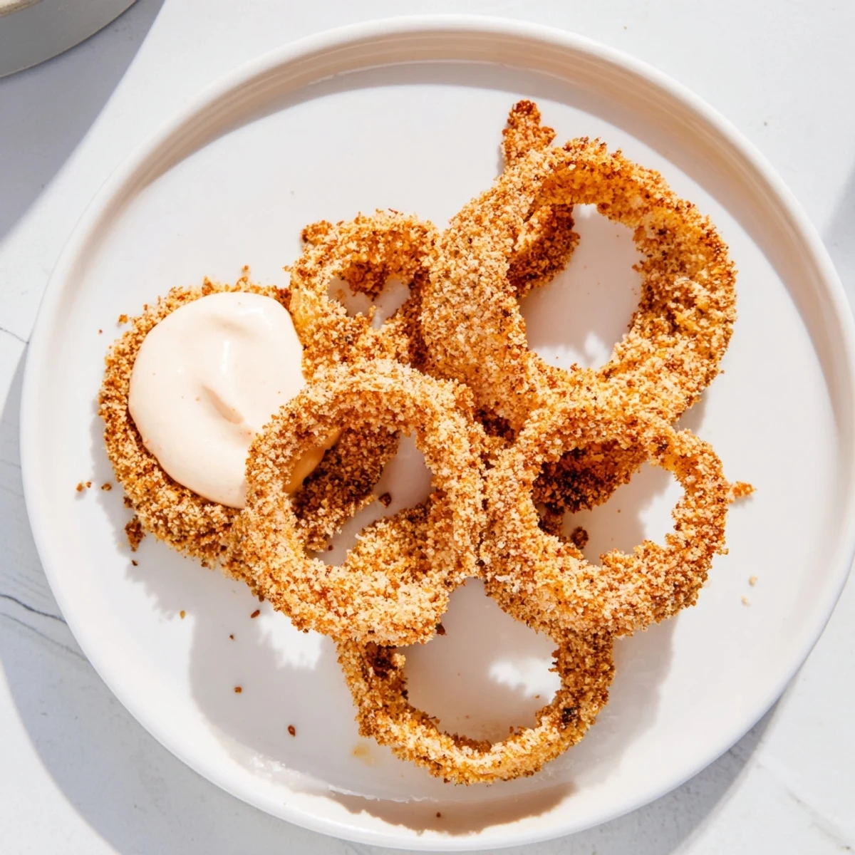 Crispy Air Fryer Onion Rings with Spicy Mayo stacked high on a rustic plate.