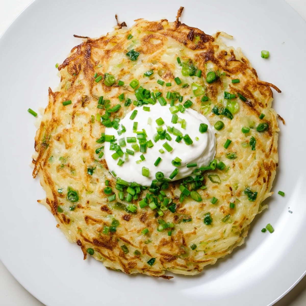 Homemade potato cakes filled with scallions, golden brown and topped with creamy sour cream and chives.