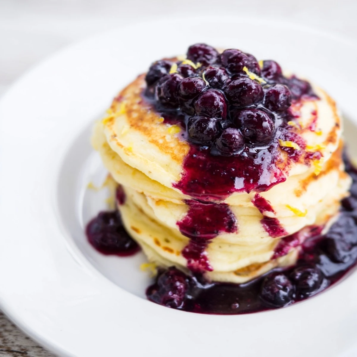 Lemon Ricotta Pancakes with Blueberry Syrup served warm, topped with berries and syrup in morning light.