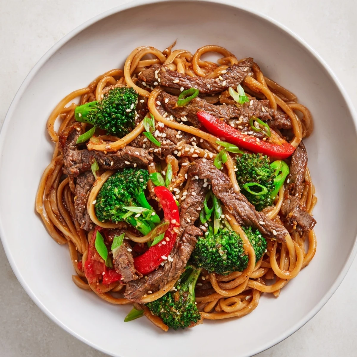 A wok-tossed serving of Beef and Broccoli Lo Mein with Sesame highlights glossy noodles, crisp broccoli, and tender beef, finished with toasted sesame seeds and green onions.