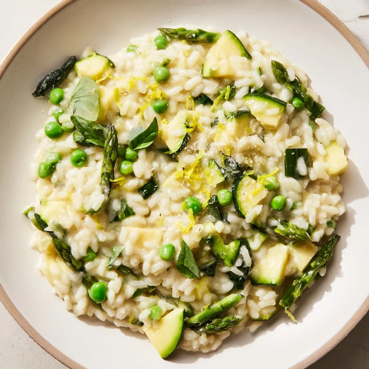 Creamy Spring Vegetable Risotto with Lemon Zest features vibrant asparagus, peas, and spinach on a rustic wooden table.