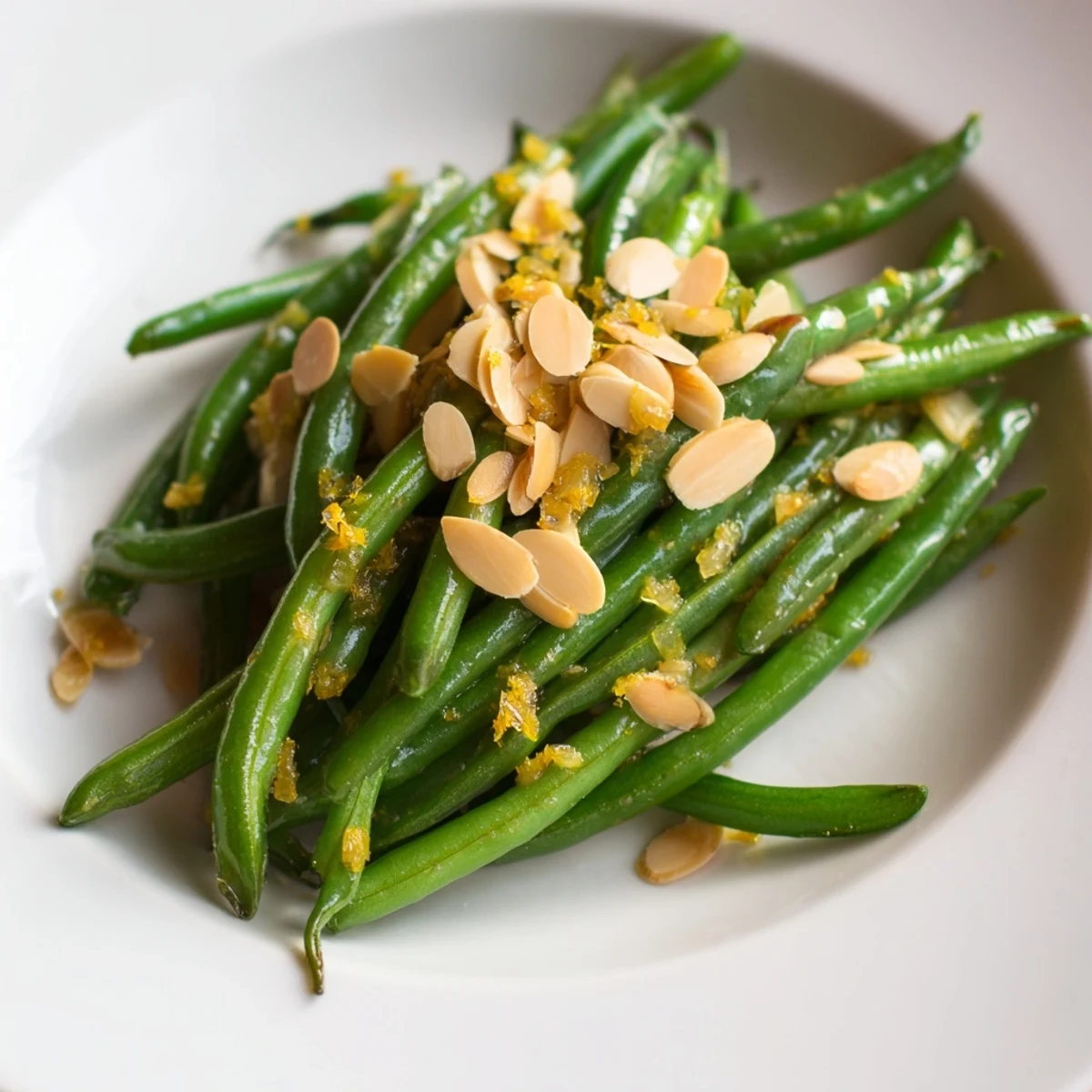 A close-up of Green Beans with Toasted Almonds and Lemon, with bright green beans and golden nuts glistening in olive oil.  