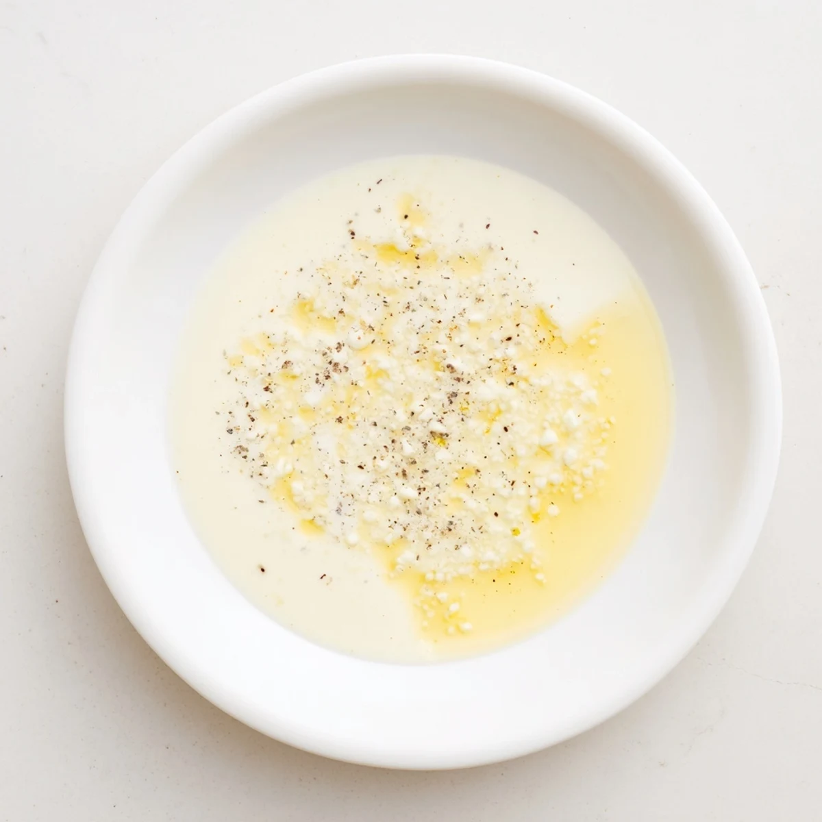 Lemon Dijon Dressing poured from a glass bottle onto roasted vegetables, highlighting its tangy, vibrant color.