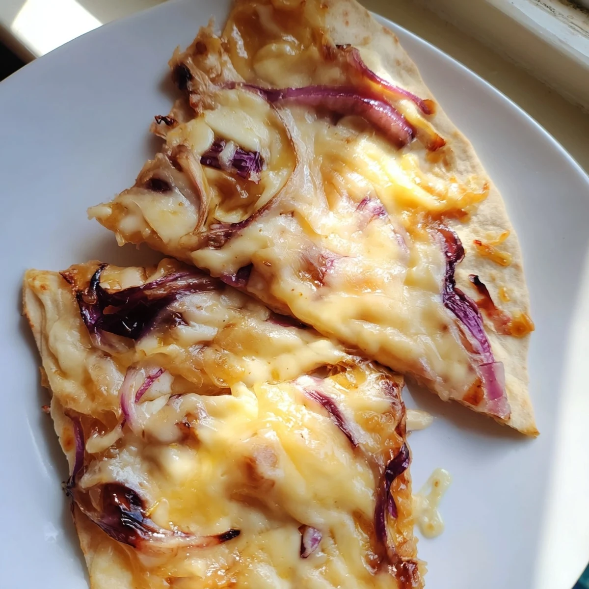 A close-up view of a slice of Sweet Heat Honey Garlic Flatbread Pizza revealing gooey cheese and vibrant bell peppers.