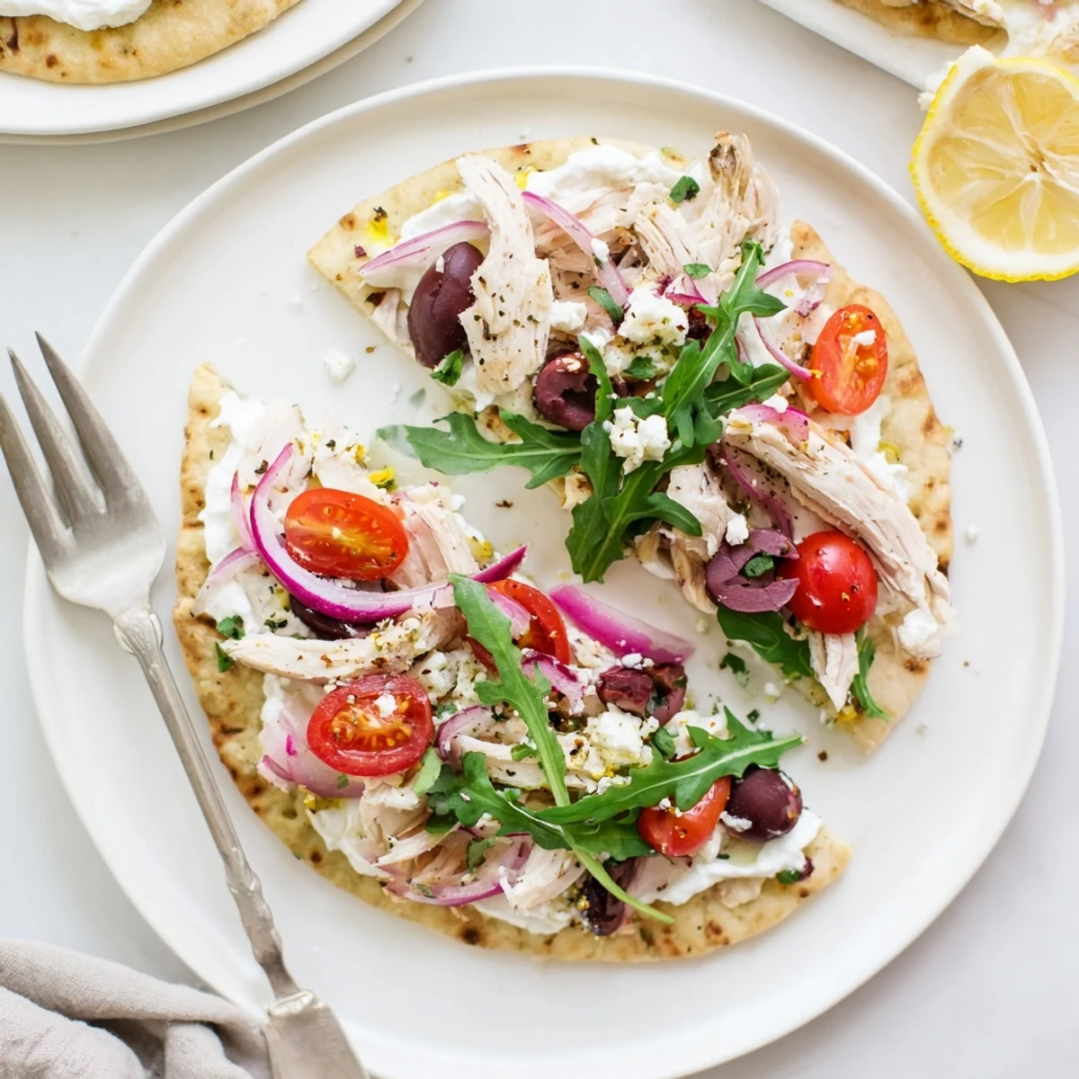 A close view of Zesty Lemon Herb Chicken Flatbread With Creamy Feta shows crumbled feta and fresh arugula on a warm, crisp base.