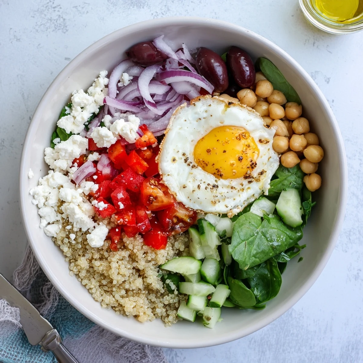 Freshly cooked eggs rest atop Mediterranean Breakfast Bowls filled with quinoa, spinach, and colorful cherry tomatoes.  