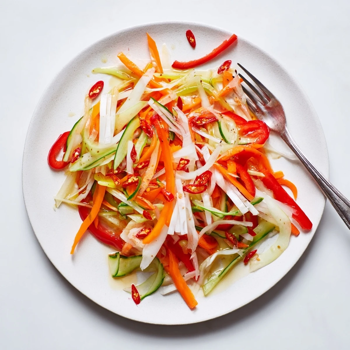 Overhead view of Vietnamese Vegetable Pickle Medley with julienned daikon and carrots in a glass jar, marinating for vibrant flavor.