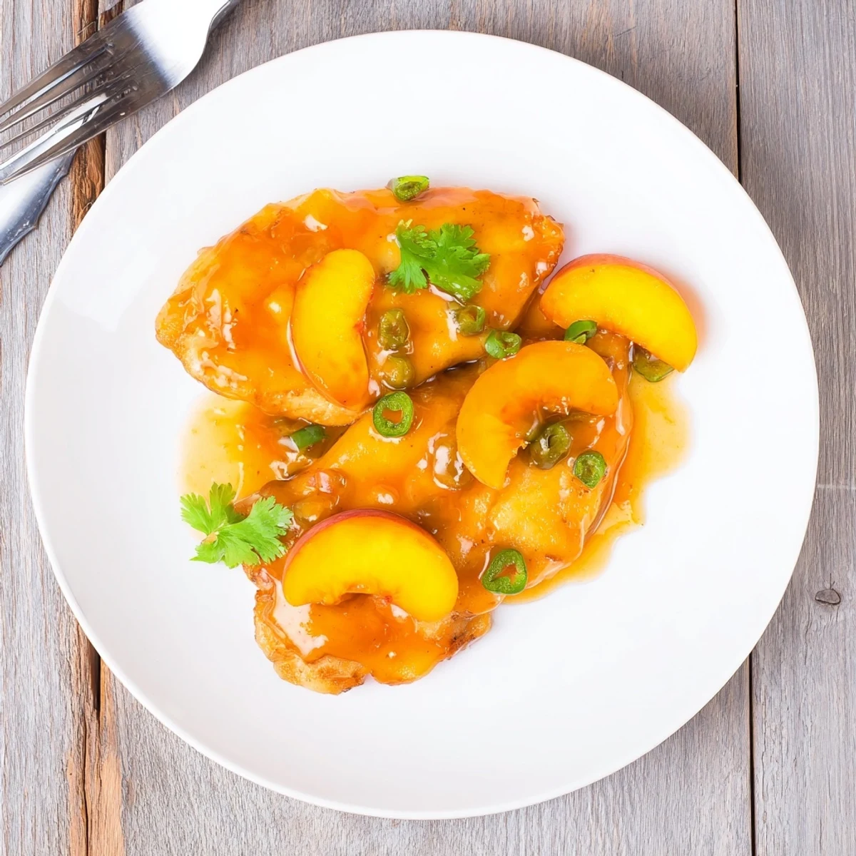 Sizzling skillet of juicy jalapeño peach glazed chicken fresh from the oven, topped with vibrant jalapeño slices and peach wedges.