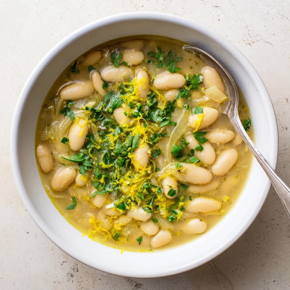 Steaming bowls of Miso Butter Brothy Beans topped with fresh herbs and lemon zest