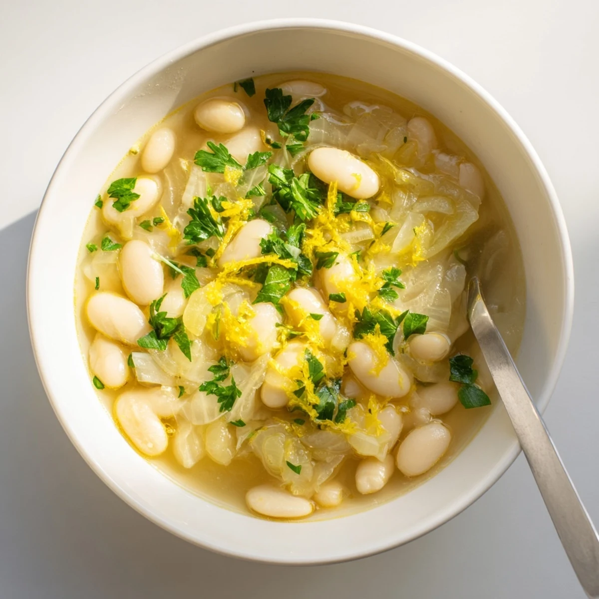 Fork-tender Miso Butter Brothy Beans with a golden butter swirl and fragrant garnish