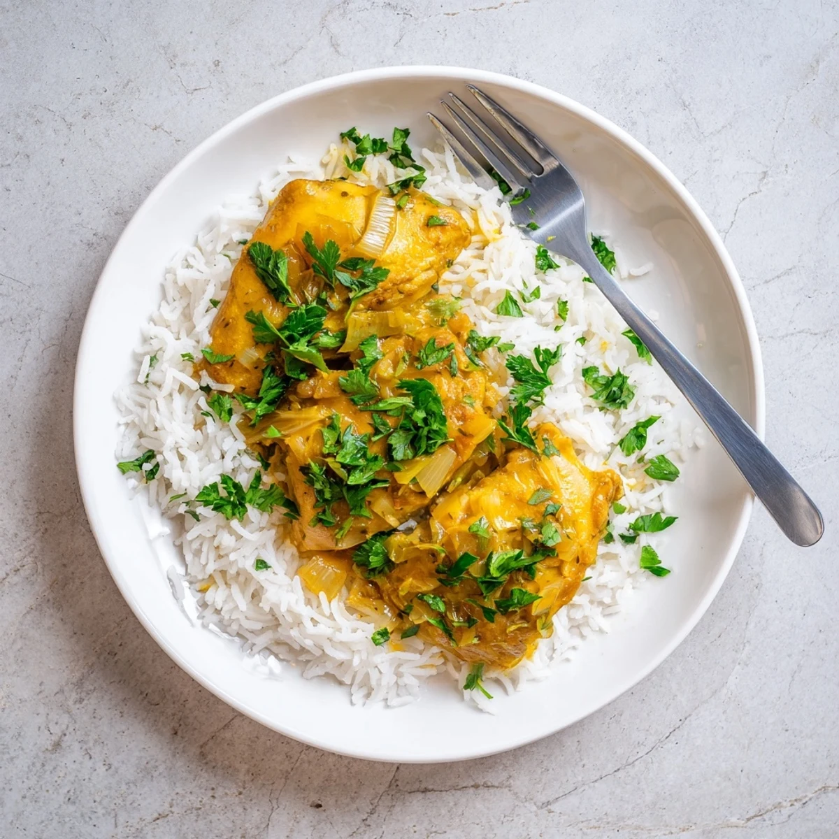 Golden-brown Slow Cooker Lemon Herb Chicken With Fluffy Rice plated beside lemon wedges and bright herbs.