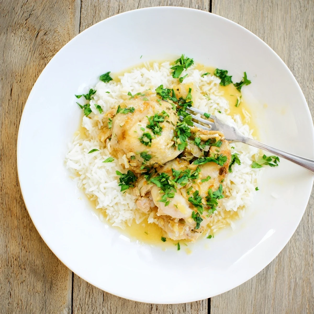 Savory Slow Cooker Lemon Herb Chicken With Fluffy Rice spooned over buttery rice with rich pan juices.