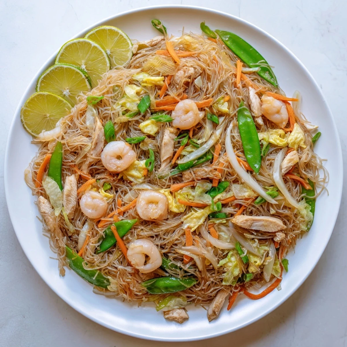 Glossy Filipino Pancit Bihon stir-fry showcasing rice noodles with vibrant cabbage and carrots in soy sauce