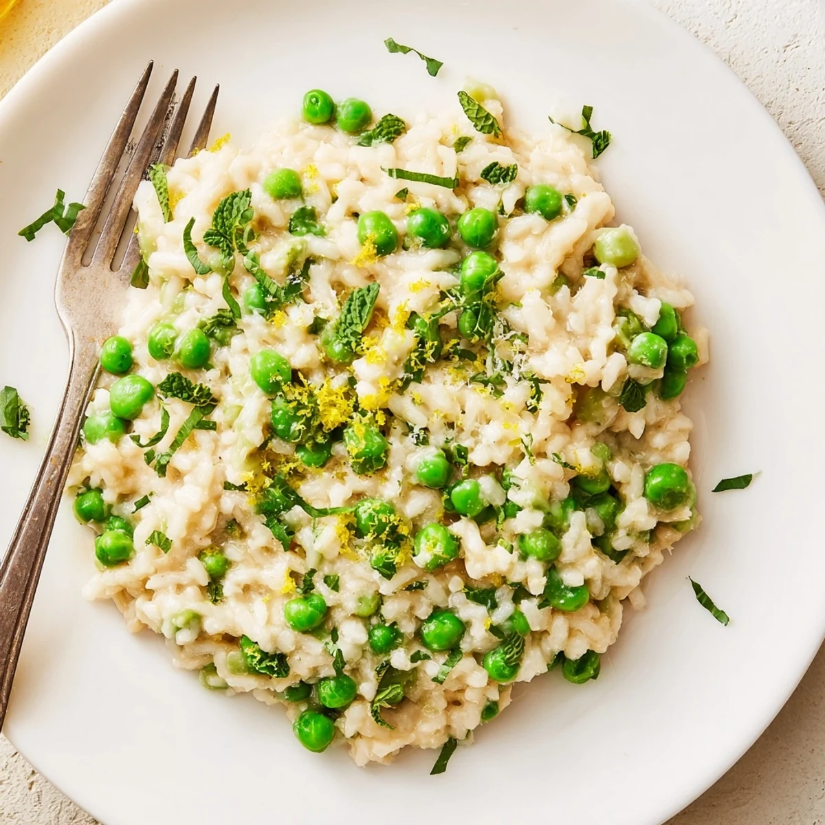 Vibrant spring pea risotto garnished with parsley and lemon zest on a rustic wooden table