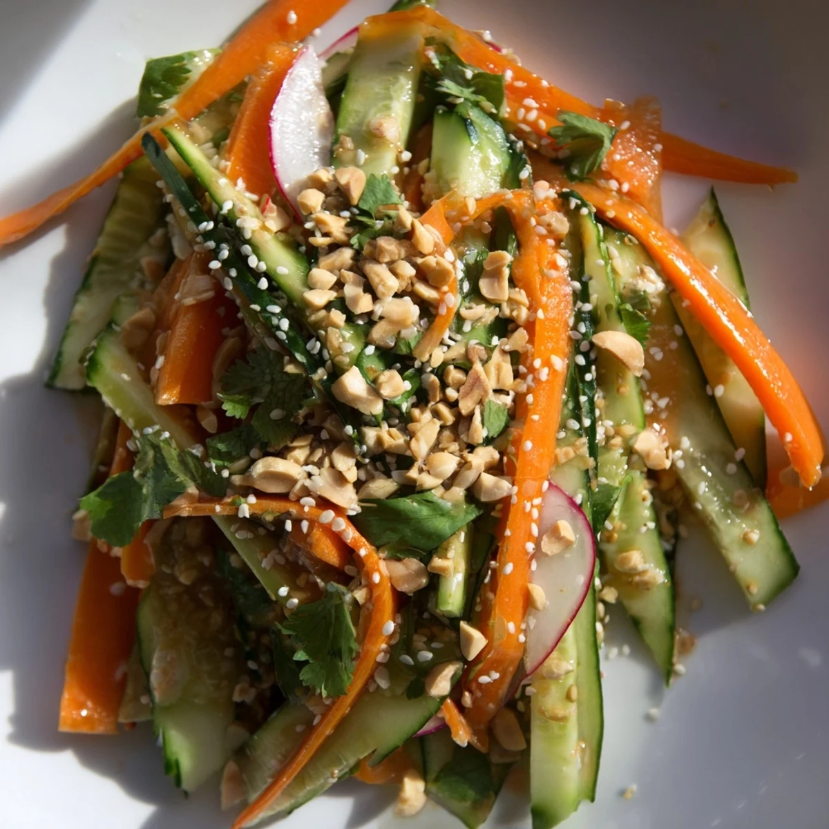 Colorful bowl of crisp cucumber carrot salad tossed with tangy Asian dressing and toasted sesame seeds