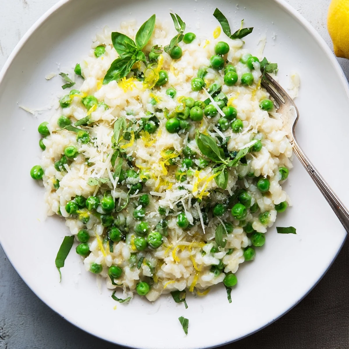 Creamy spring pea risotto topped with grated Parmesan and fresh green basil leaves