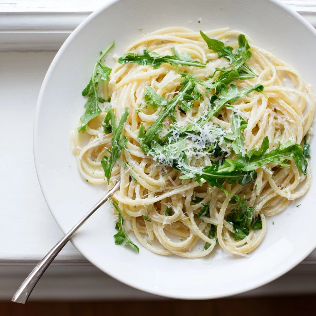 Bowl of lemon ricotta pasta featuring al dente noodles and fresh arugula garnished with Parmesan