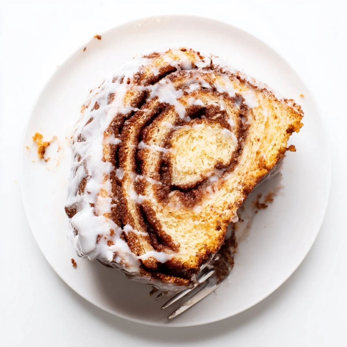 Golden cinnamon roll cake with spiraled cinnamon sugar ribbons drizzled with sweet white vanilla glaze