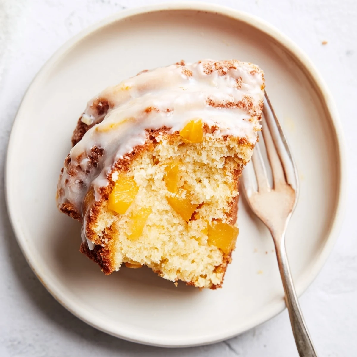 Sliced peach cobbler pound cake showing juicy peach pieces and warm cinnamon swirls