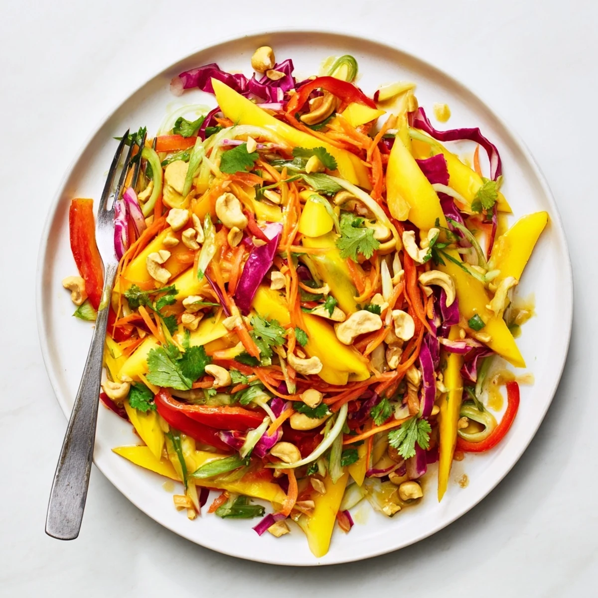 Colorful mango slaw featuring julienned vegetables and cilantro drizzled with citrus dressing