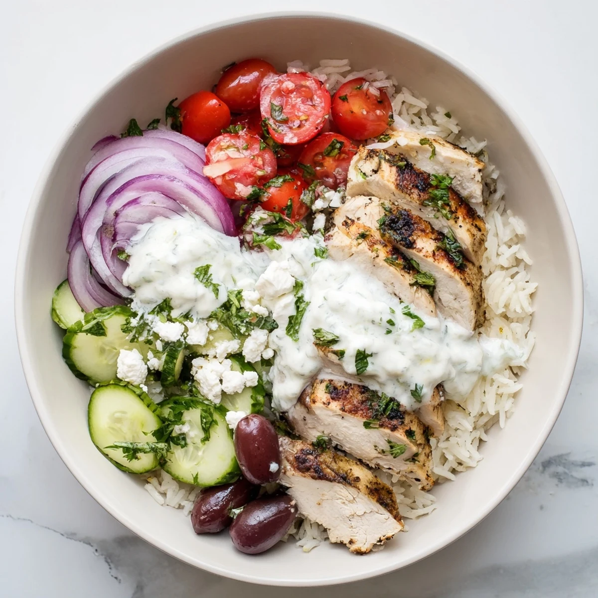 Golden sliced Greek chicken bowls over fluffy rice with colorful Mediterranean vegetables and creamy yogurt sauce