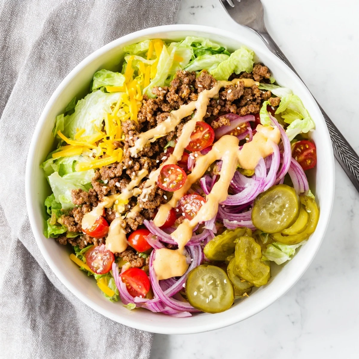 Burger bowl featuring seasoned ground beef over crisp lettuce with cherry tomatoes and tangy special sauce.