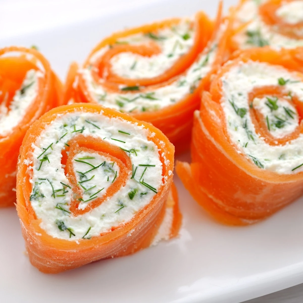 Appetizer platter featuring smoked salmon roll ups with cream cheese and fresh dill garnish