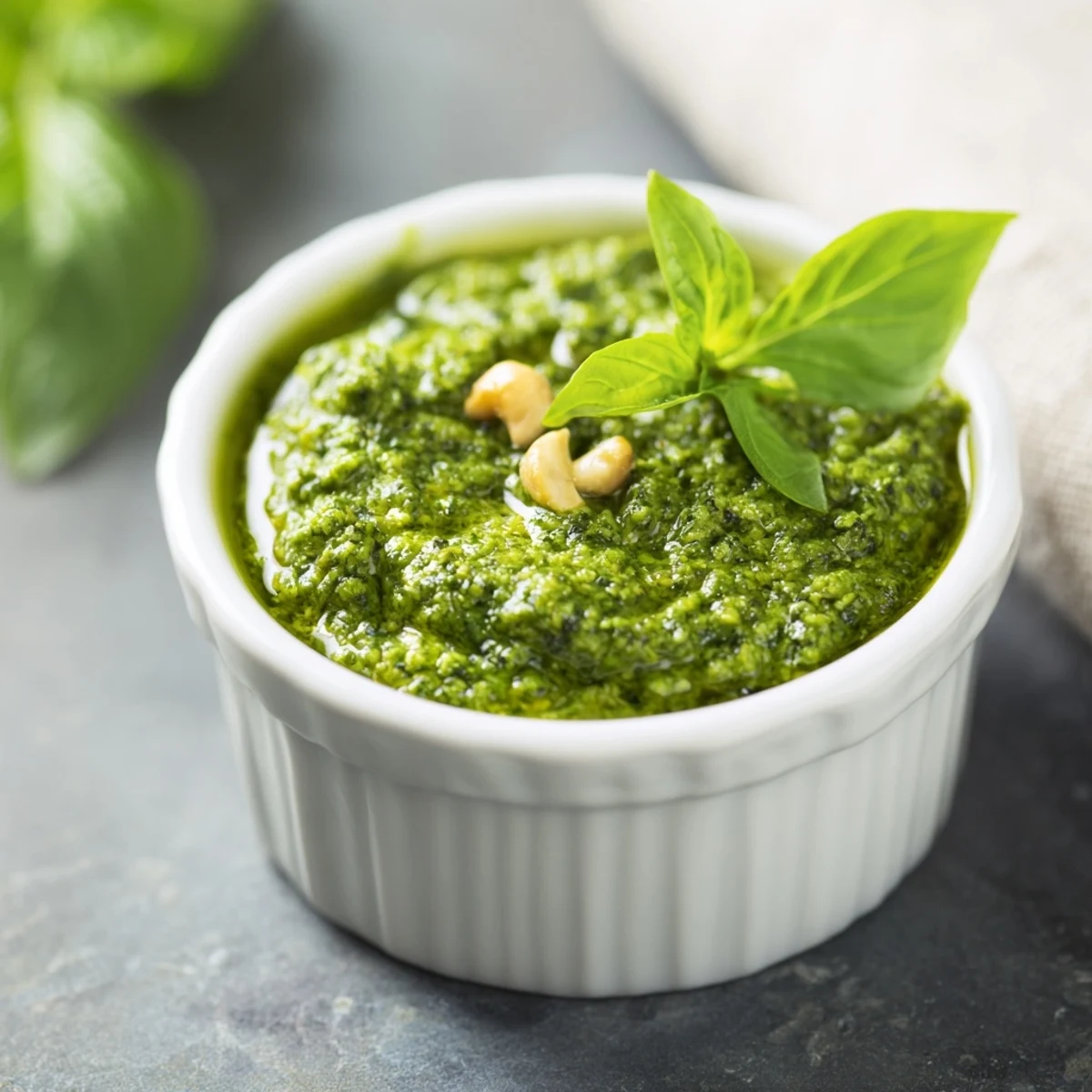 Vibrant green Thai basil pesto swirled in a rustic white ceramic bowl