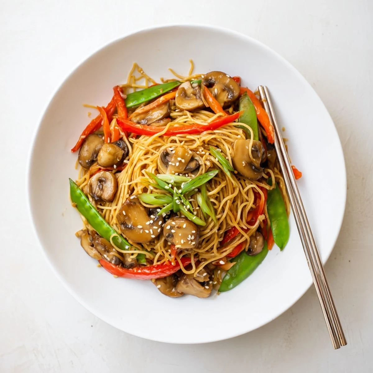 Gardein mushroom chow mein stir-fry with vegetables in a white bowl on wooden table