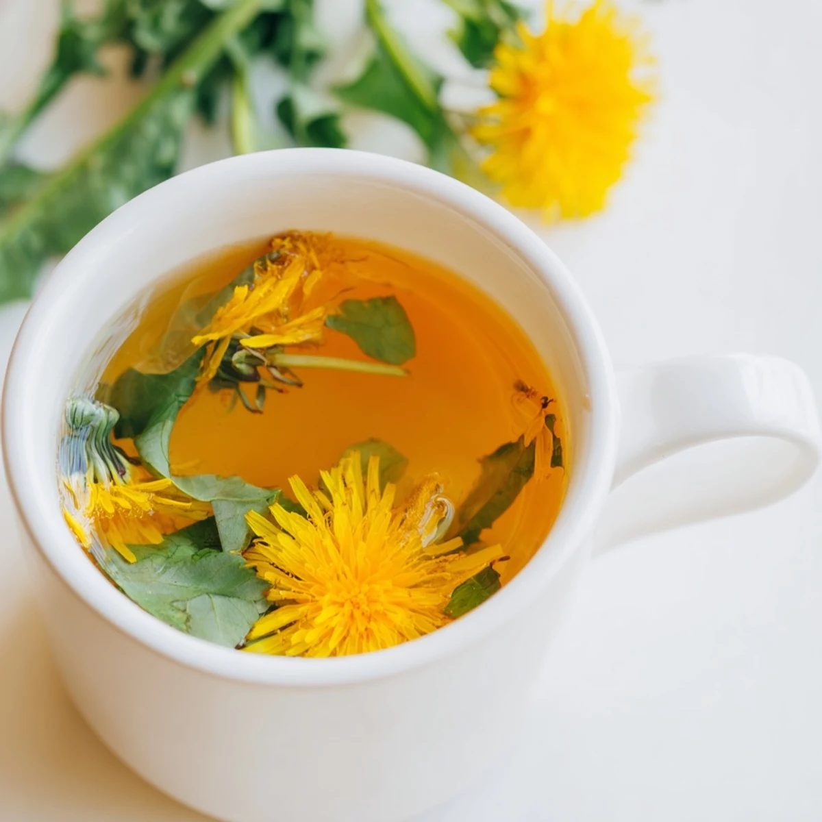 Steaming cup of dandelion tea with bright yellow petals floating in clear amber liquid