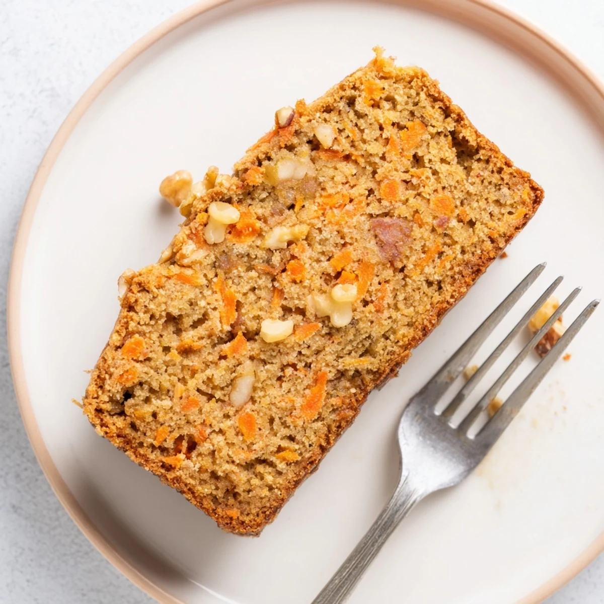 Moist carrot cake banana bread loaf topped with cream cheese frosting and chopped walnuts