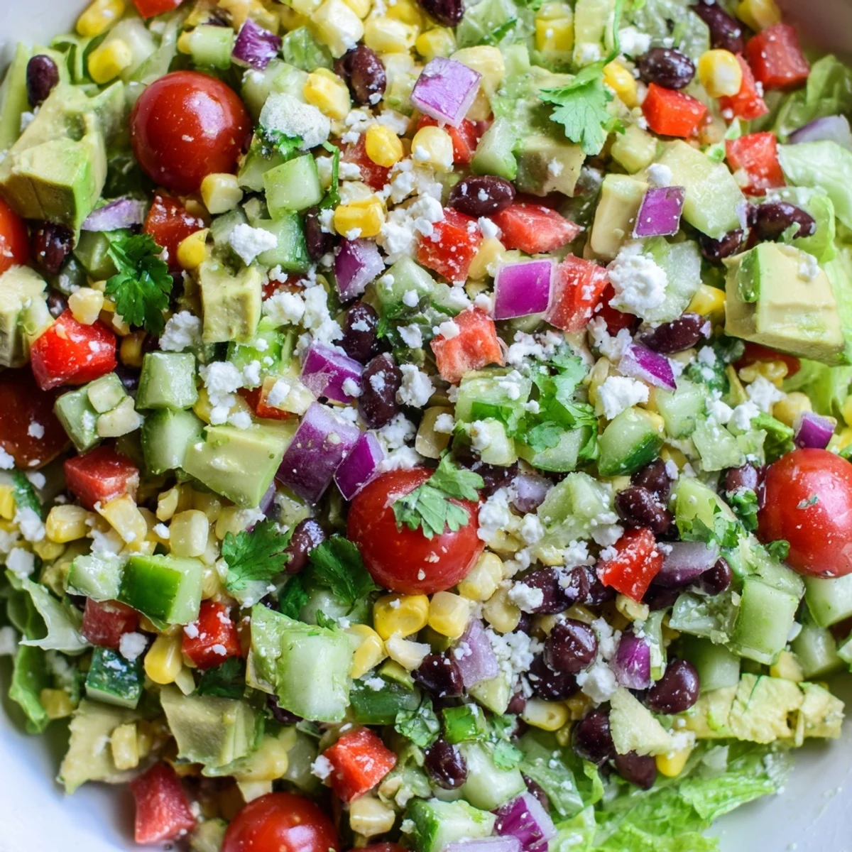 Mexican chopped salad in a serving bowl tossed with zesty lime cilantro dressing and cheese