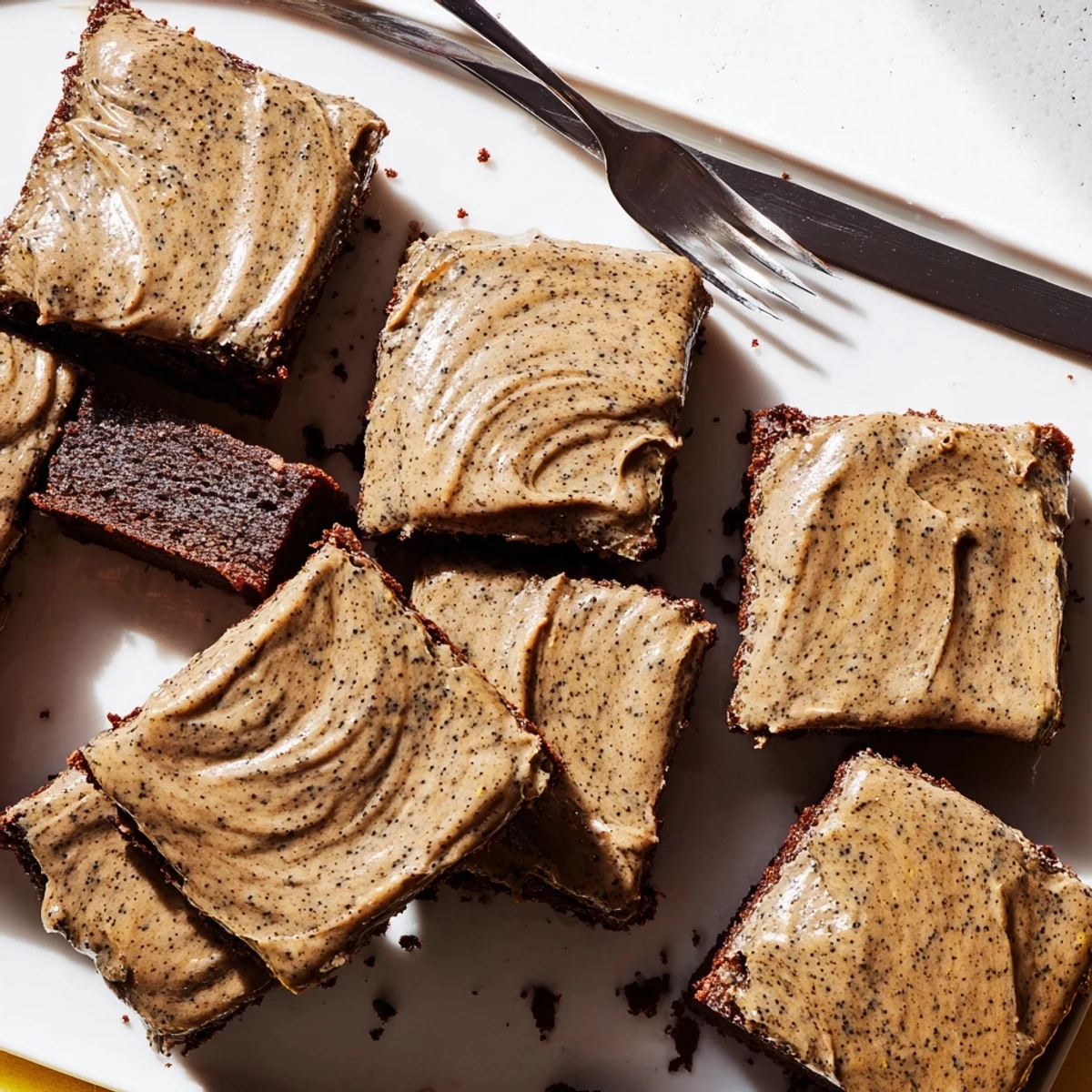 Thick fudgy banana bread brownie squares topped with creamy brown butter frosting and scattered powdered sugar