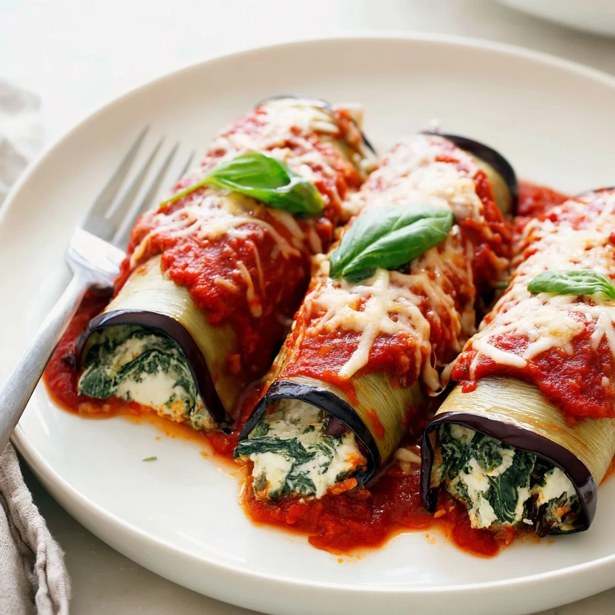 Sliced and plated, Healthy Eggplant Rollatini with marinara drizzle and parsley