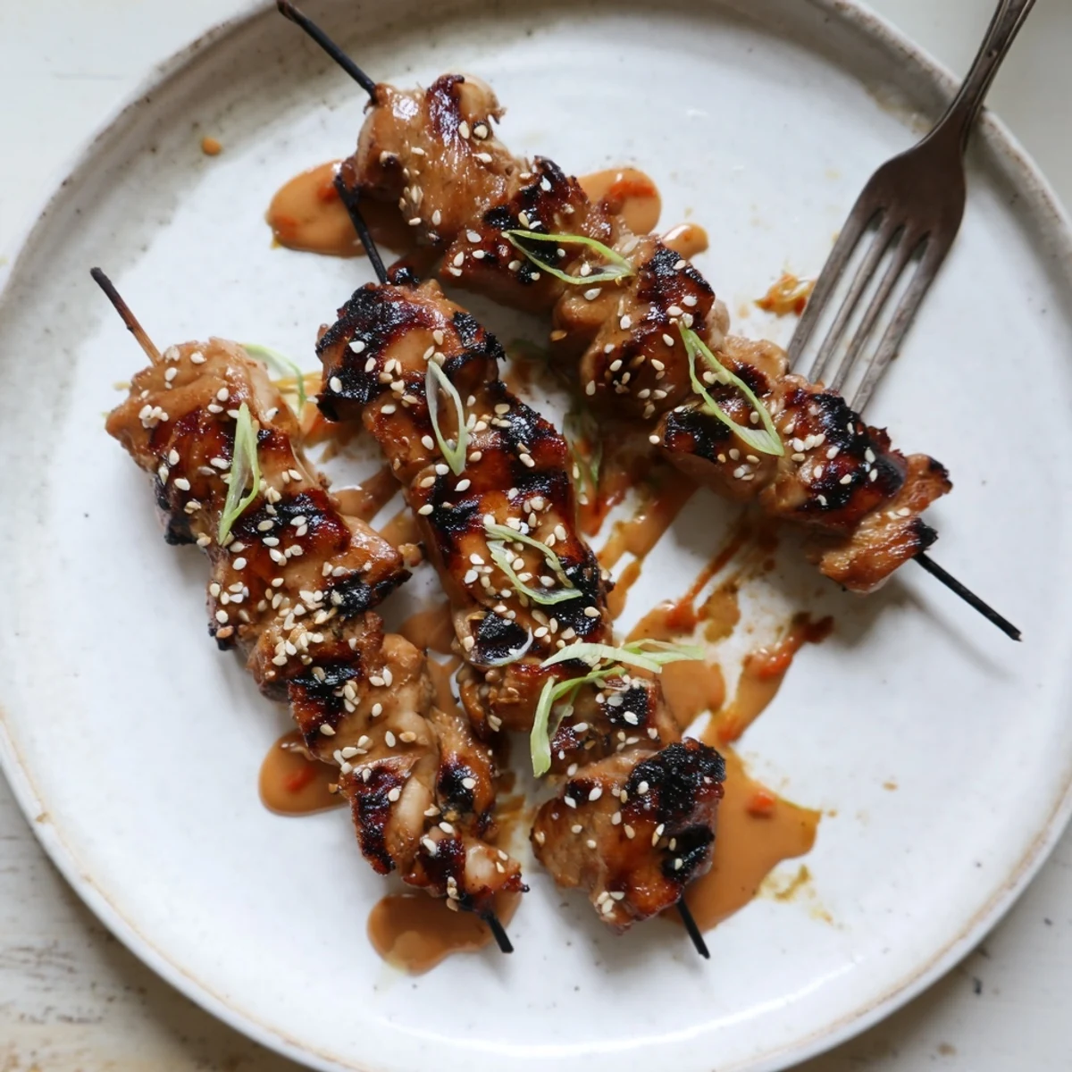 Grilled Bang Bang Chicken Skewers glazed with creamy spicy sauce, sesame garnish.