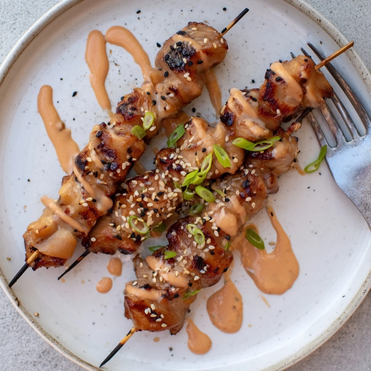 Savory Bang Bang Chicken Skewers steaming hot, sprinkled with sesame and scallions.
